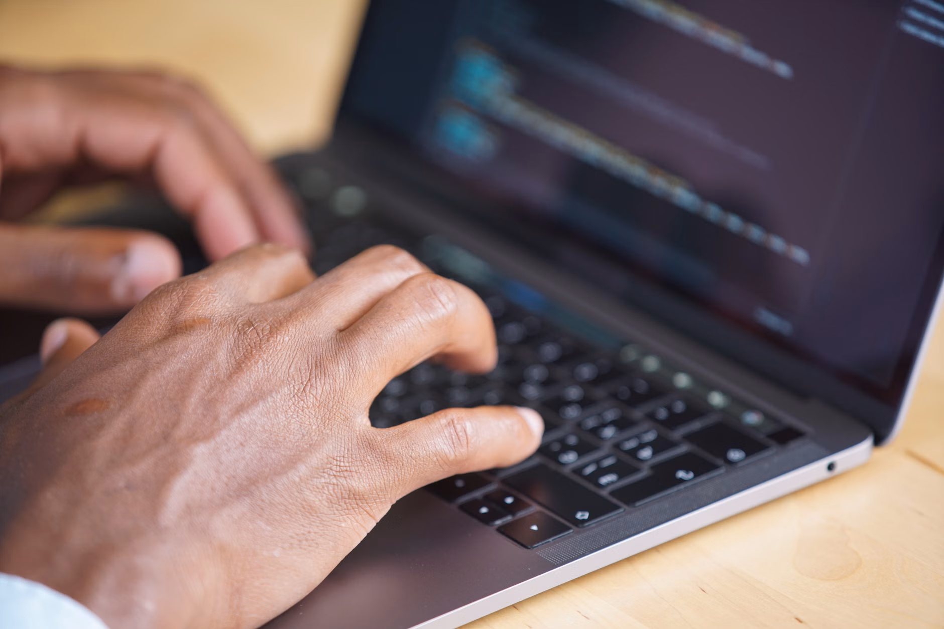 Mani che digitano su un laptop con il codice visualizzato sullo schermo, che mostra l'uso della tecnologia.