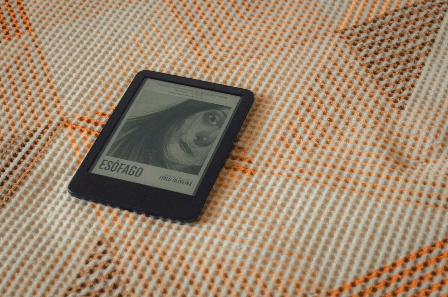 Lector de ebooks mostrando la portada de un libro sobre una manta acogedora texturizada.